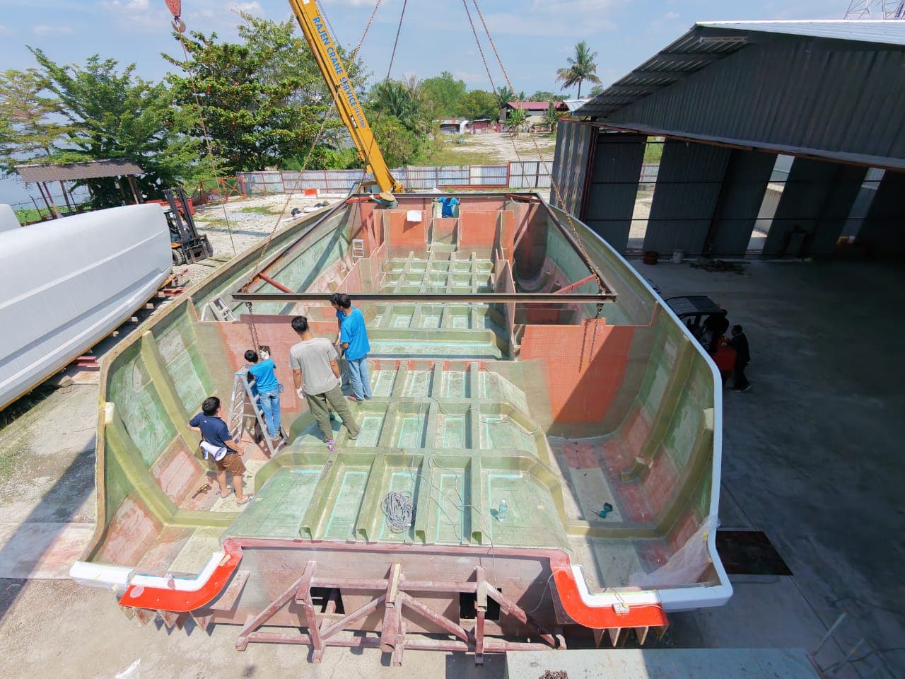 Top-down view of workers prepping the inside of an open hull mold